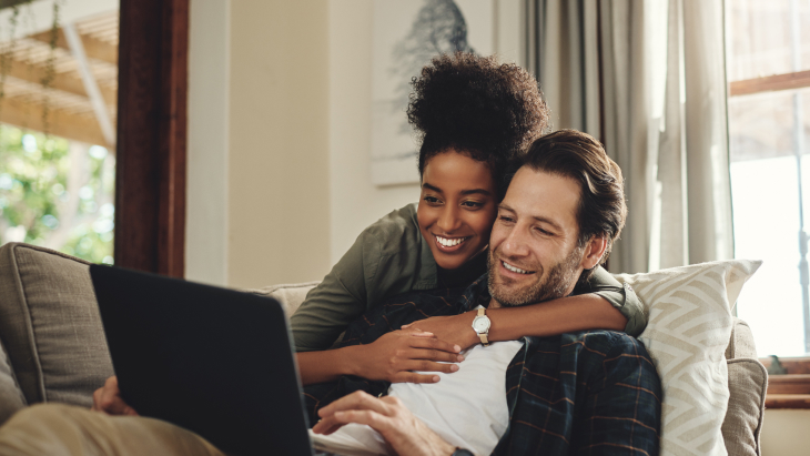 Laptop, streaming and an interracial couple watching a movie using an online subscription service for entertainment. Computer, relax or internet with a man and woman bonding together over a video