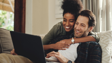 Laptop, streaming and an interracial couple watching a movie using an online subscription service for entertainment. Computer, relax or internet with a man and woman bonding together over a video