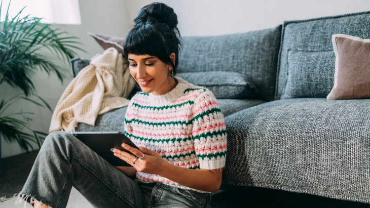 A young female sitting on the floor looking at her tablet