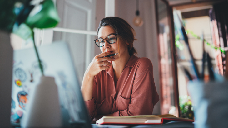 Young businesswoman thinking about something while sitting front open portable laptop computer