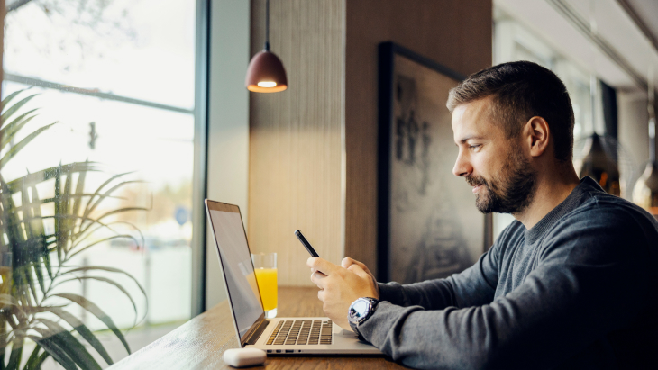 coffee shop and working on social media by using phone and laptop.