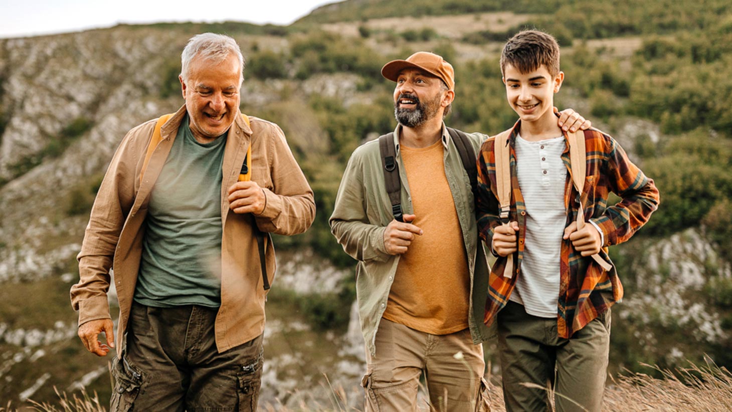 Happy older father with adult son and grandson out walking and admiring nature.