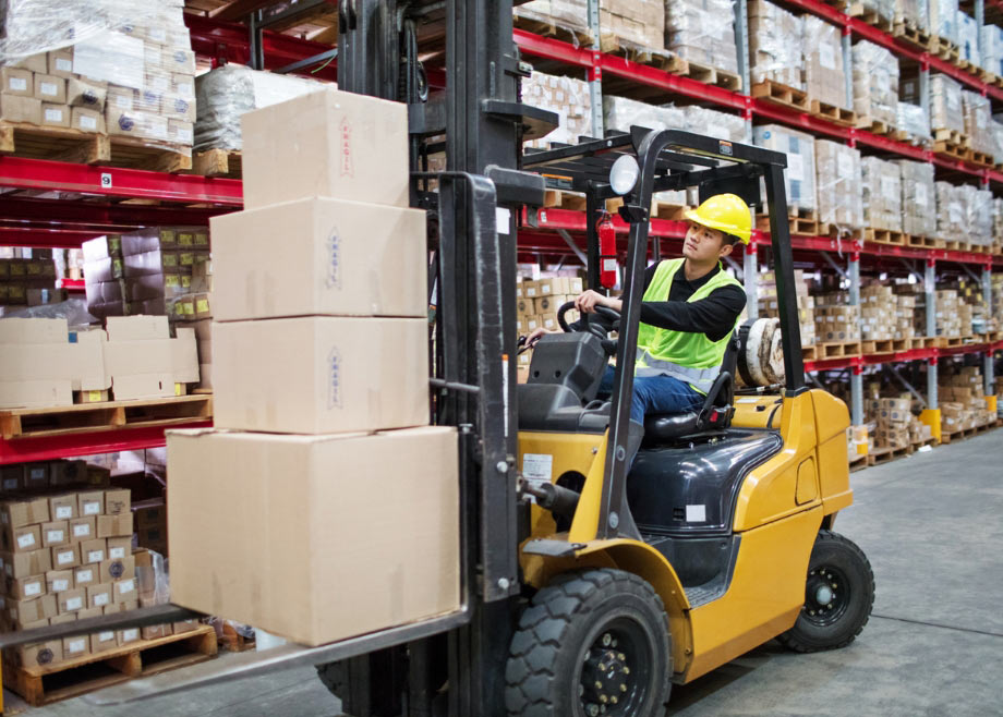 Man moving load with forklift loader in warehouse